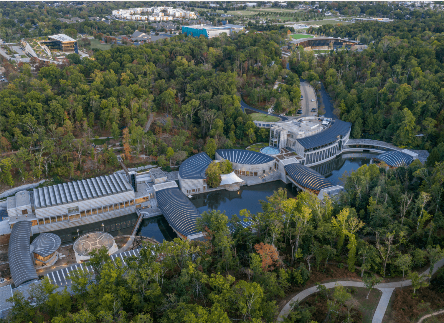 Aerial view of a forested campus of four buildings with unique architecture