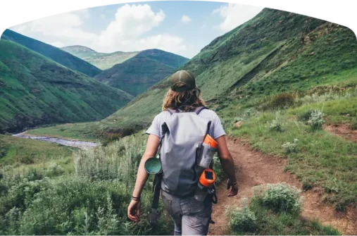 A person hiking in a valley surrounded by mountains on both side