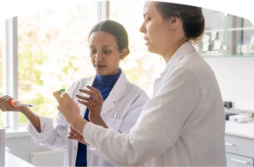 2 ladies in white lab coats working in a lab